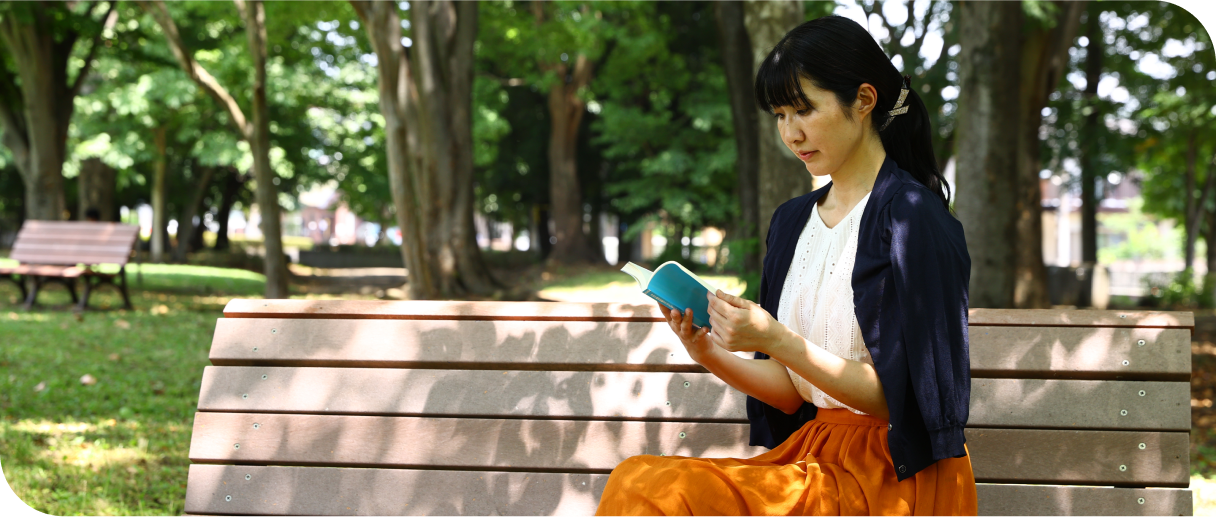Lady sitting on a park bench, reading from a book