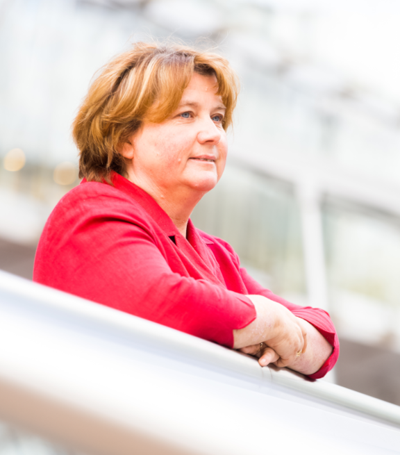 Lady leaning on railing and looking off into the distance with a slight smile on her face
