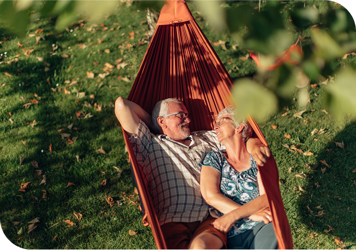 Elderly couple laying in a hammock over grass
